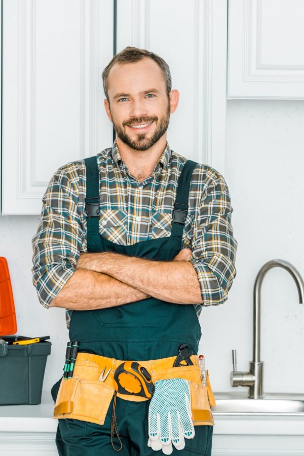 smiling-handsome-plumber-standing-with-crossed-arms-and-looking-at-camera-in-kitchen.jpg